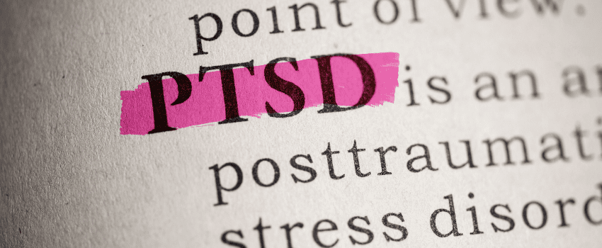 Magnified book page with highlighted text PTSD in pink, suggesting a person studying the text